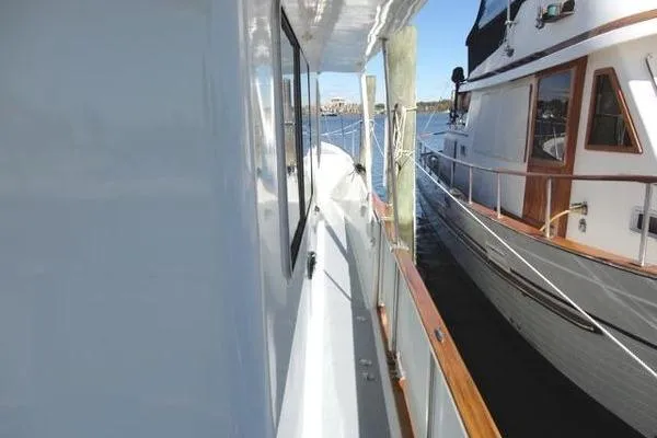 Slide: The Image of 1985 Pearson 43 Trawler docked beside another boat, showcasing side deck and railing. - 53