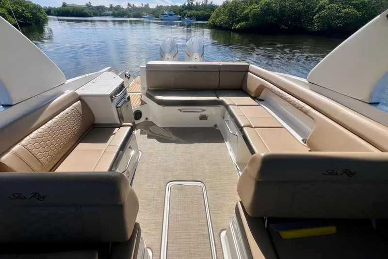 Slide: The Image of 2019 Sea Ray SDX 290 Outboard boat interior with tan seating and scenic water view. - 17