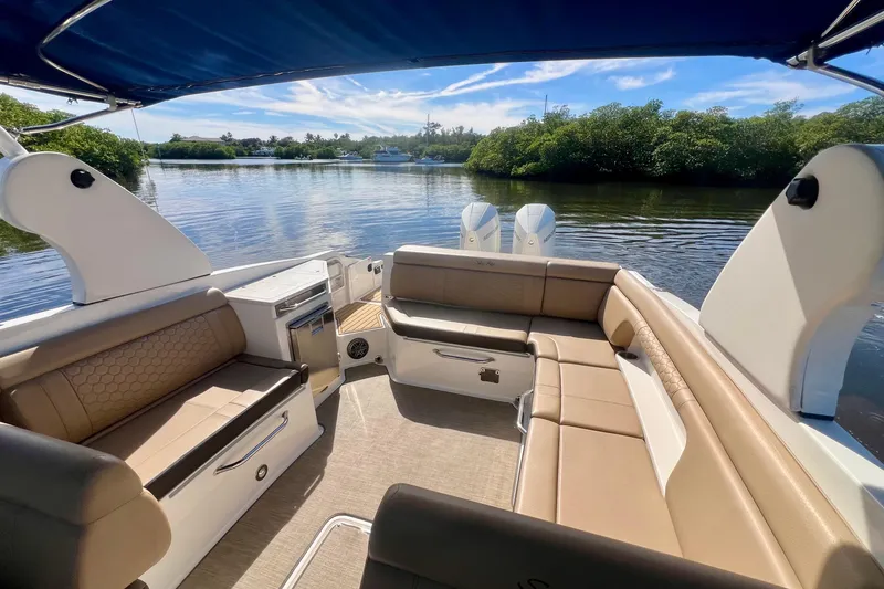 Slide: The Image of 2019 Sea Ray SDX 290 Outboard boat interior with tan seating and scenic water view. - 18