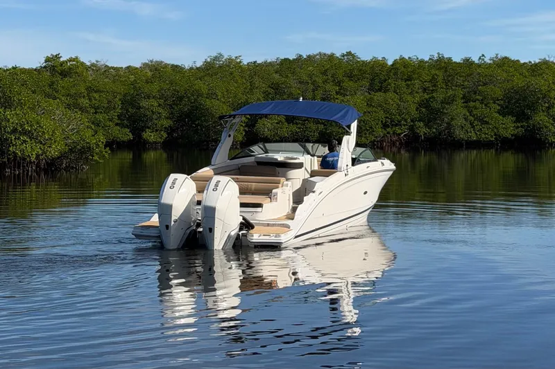 Slide: The Image of 2019 Sea Ray SDX 290 Outboard boat on calm water, surrounded by lush greenery. - 4