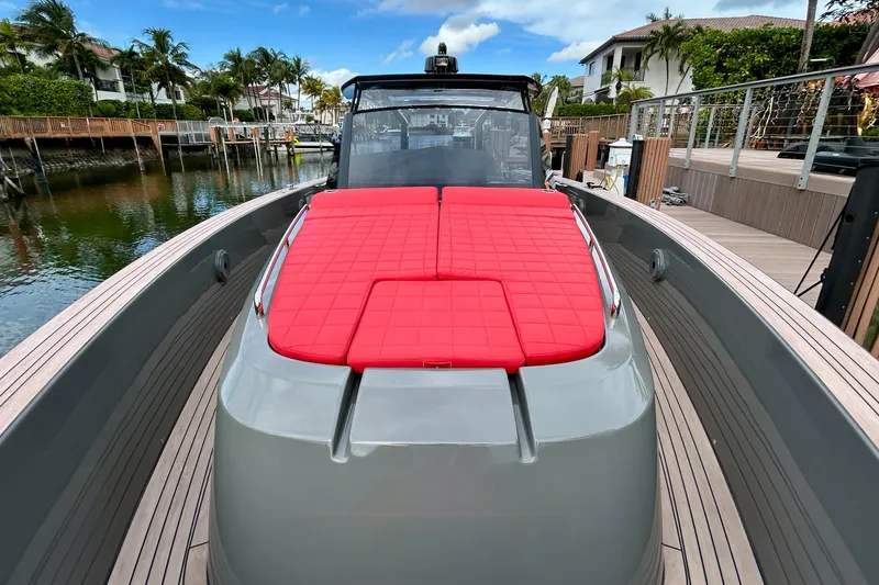 Slide: The Image of 2023 Pardo Yachts 43 with red cushioned deck, docked by waterfront homes. - 26
