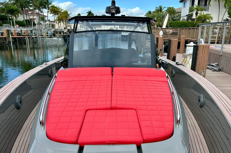 Slide: The Image of 2023 Pardo Yachts 43 with red cushioned deck, docked in a scenic marina. - 27