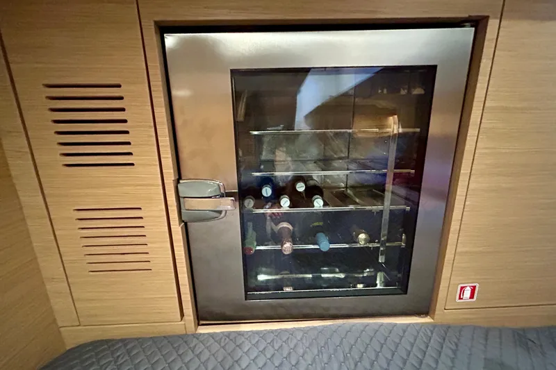 Slide: The Image of Wine cooler inside 2023 Pardo Yachts 43, featuring wooden cabinetry and glass door. - 48