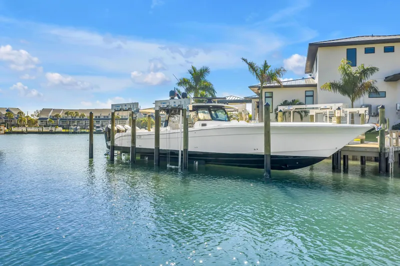 Slide: The Image of 2023 HCB 53 Suenos RXV boat docked in a scenic waterfront setting. - 2