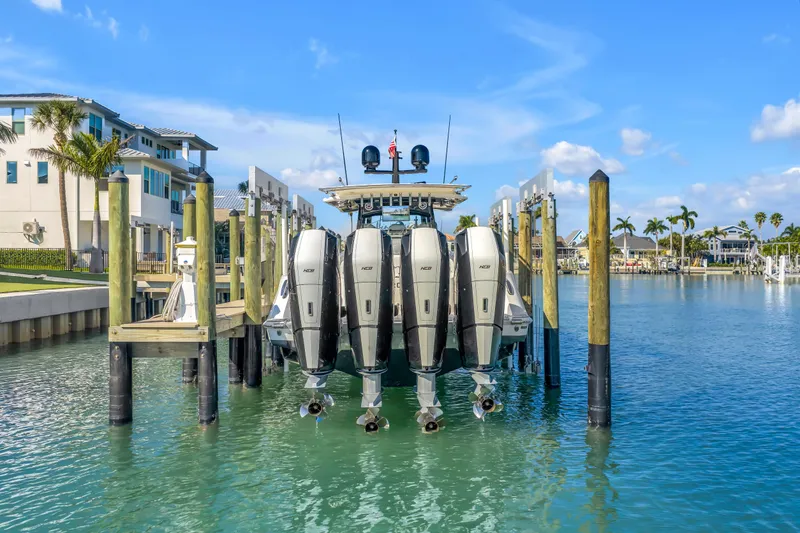 Slide: The Image of 2023 HCB 53 Suenos RXV boat docked with four powerful engines, surrounded by waterfront homes. - 5