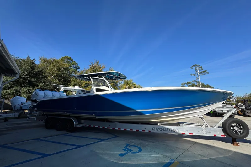 Slide: The Image of 2016 Nor-Tech 390 Sport Center Console boat on trailer, vibrant blue hull, parked outdoors. - 10