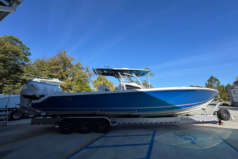 Slide: The Image of 2016 Nor-Tech 390 Sport Center Console boat on trailer, blue hull, parked outdoors. - 11