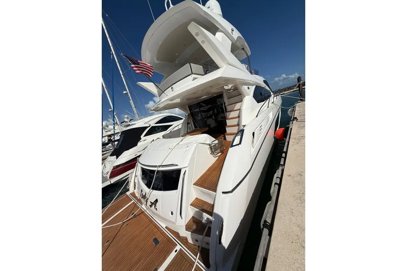 Slide: The Image of 2017 Sunseeker Manhattan 65 yacht docked, featuring sleek design and American flag. - 8
