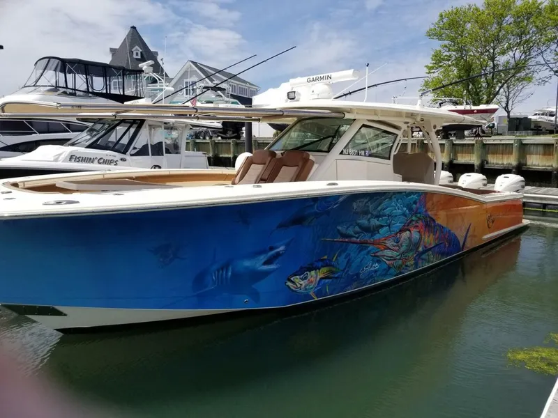 The Image of 2019 Scout 380LXF boat with colorful fish artwork docked in harbor. - 0