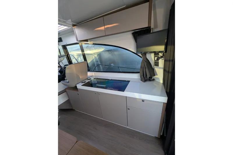 Slide: The Image of 2024 Beneteau Antares 11 interior kitchen with sink, stove, and seating area. - 11