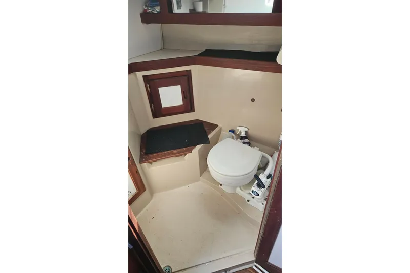 Slide: The Image of 1988 Catalina 34 sailboat bathroom with toilet and storage shelves. - 11