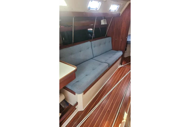 Slide: The Image of 1988 Catalina 34 interior with blue cushioned seating and wooden flooring. - 16