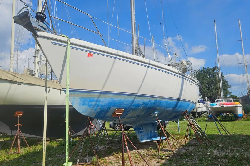 Slide: The Image of 1988 Catalina 34 sailboat on stands in a boatyard under a clear blue sky. - 30