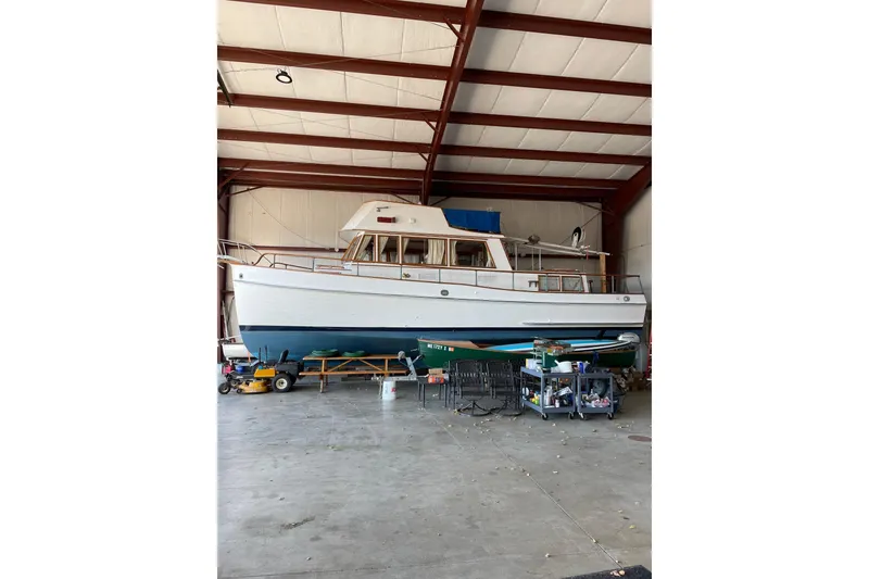 The Image of 1978 Grand Banks GB36570 boat in storage, surrounded by tools and equipment. - 1