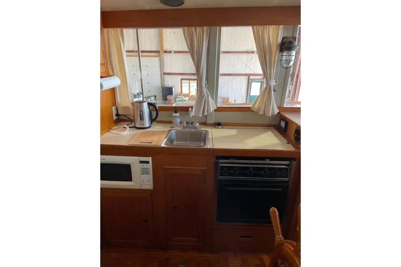Slide: The Image of 1978 Grand Banks GB36570 boat kitchen with sink, stove, microwave, and curtains. - 22