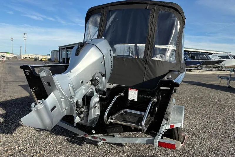 Slide: The Image of 2026 Smoker Craft Osprey 162 boat with outboard motor, parked on a trailer. - 2