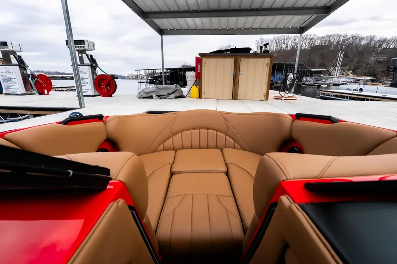 Slide: The Image of 2026 MB B52 23 Classic boat interior with red dashboard and tan seating at a marina. - 21