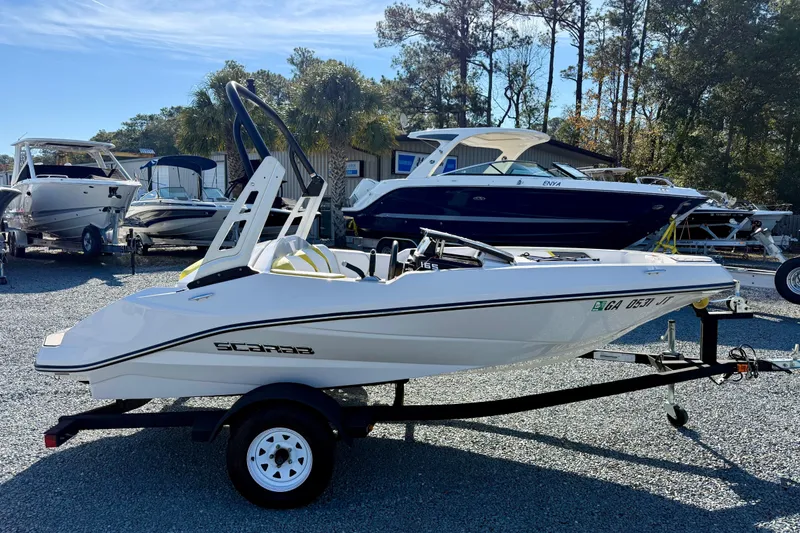 Slide: The Image of 2017 Scarab 165 G boat on trailer, parked in a marina with other boats. - 6