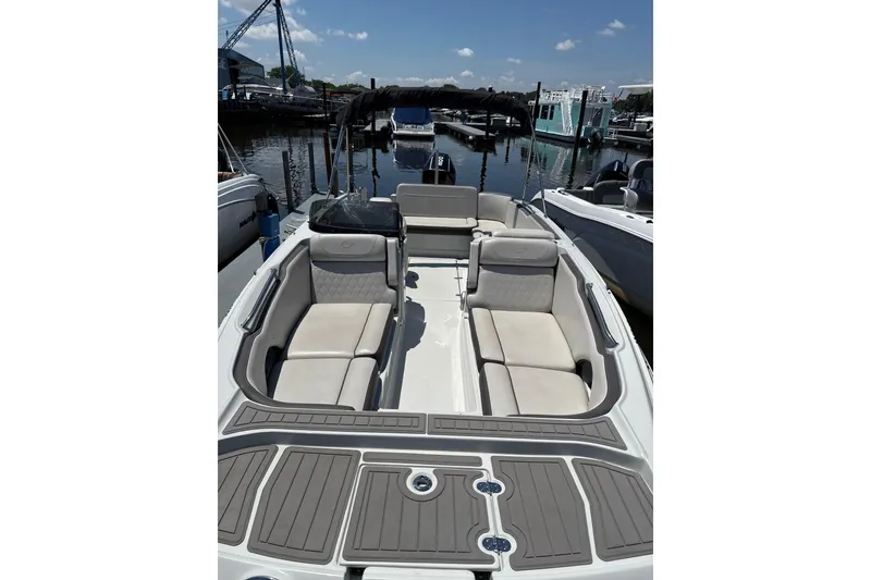 Slide: The Image of 2024 Crownline Eclipse E230 XS boat interior with spacious seating at a marina. - 4