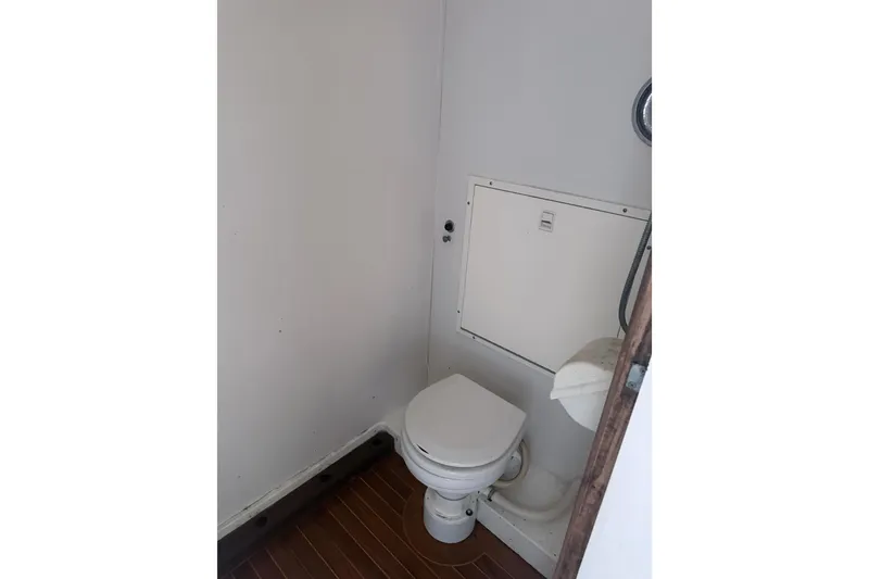 Slide: The Image of Compact bathroom in 1995 Bertram 46 Moppie boat with white toilet and wooden floor. - 11