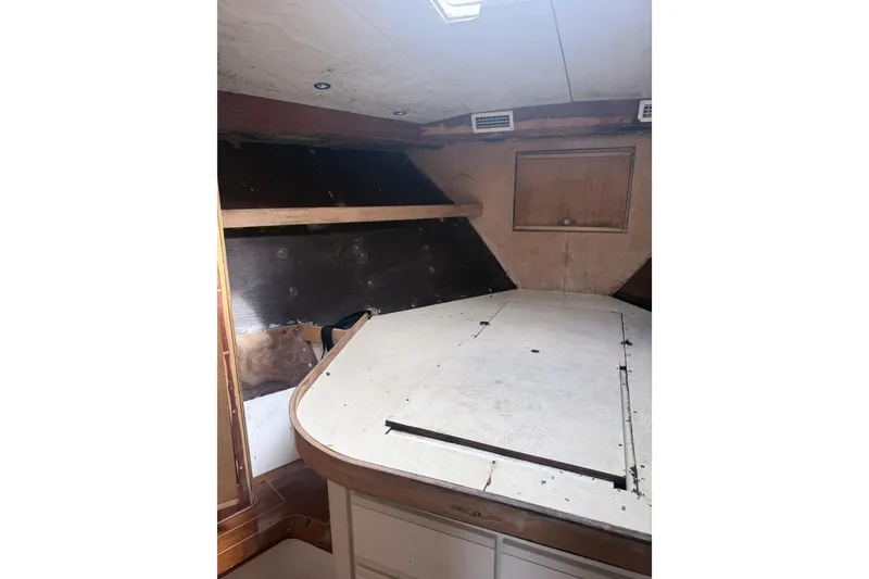 Slide: The Image of Interior cabin of a 1995 Bertram 46 Moppie boat, featuring a wooden table and storage. - 14