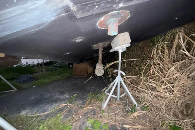 Slide: The Image of Bottom view of a 1995 Bertram 46 Moppie boat on stands, surrounded by grass. - 18