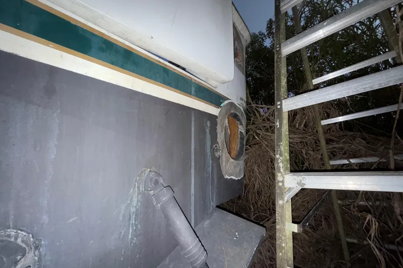 Slide: The Image of 1995 Bertram 46 Moppie boat hull with ladder, showing wear and outdoor setting. - 19