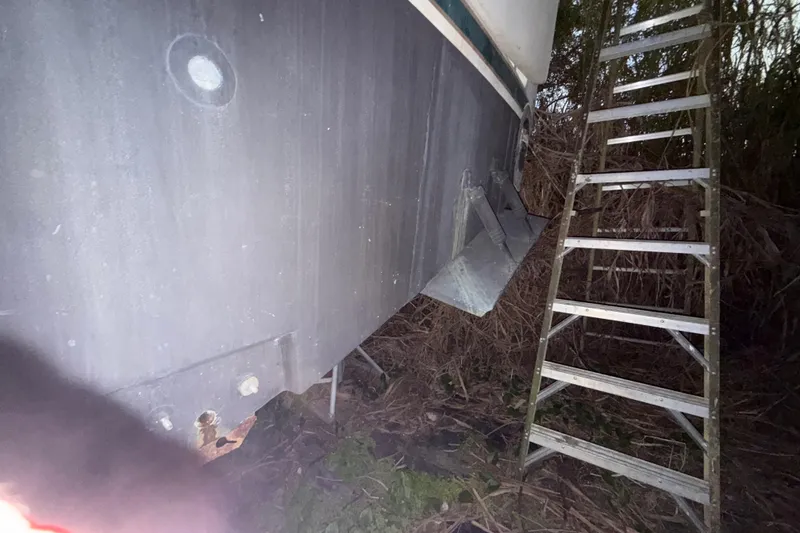 Slide: The Image of 1995 Bertram 46 Moppie boat hull with ladder, in outdoor setting. - 20