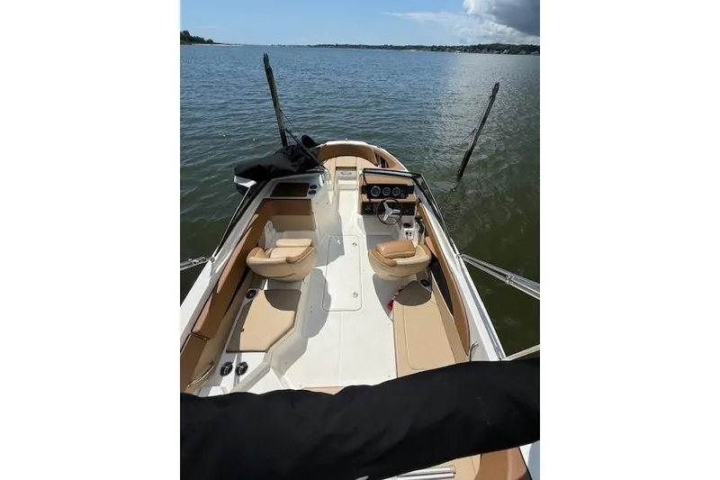 Slide: The Image of 2018 Sea Ray SPX 210 Outboard boat interior with tan seating on a calm lake. - 15