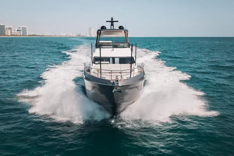 Slide: The Image of 2023 Azimut Fly 68 yacht cruising on open sea with city skyline in background. - 59