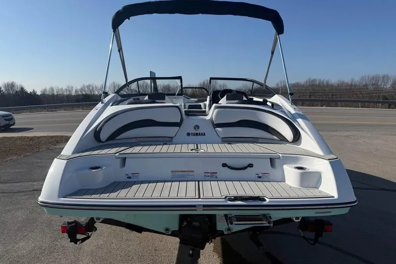 Slide: The Image of 2026 Yamaha Boats SX195, rear view, parked on pavement under clear blue sky. - 5