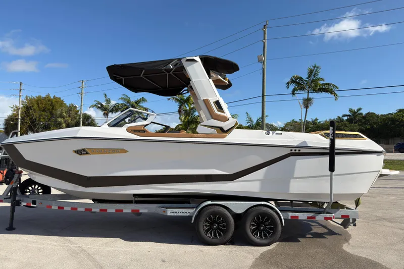 Slide: The Image of 2025 Nautique Super Air Nautique G25 Paragon boat on trailer, sunny day, palm trees. - 13