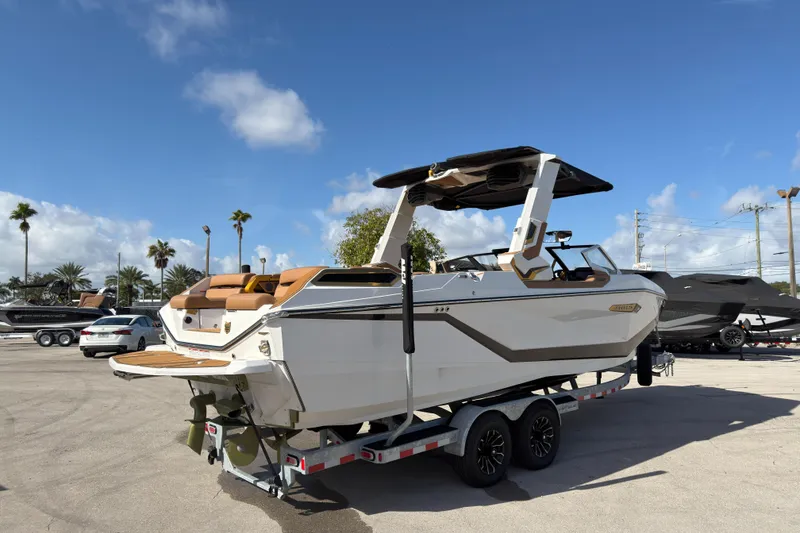 Slide: The Image of 2025 Nautique Super Air Nautique G25 Paragon boat on trailer under blue sky. - 2
