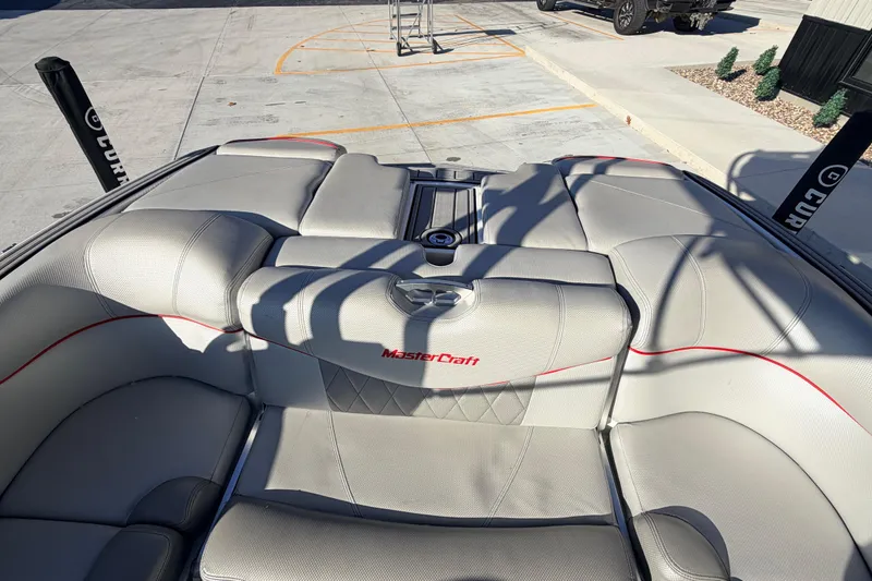 Slide: The Image of 2015 MasterCraft X20 boat interior with gray seating and red accents. - 24