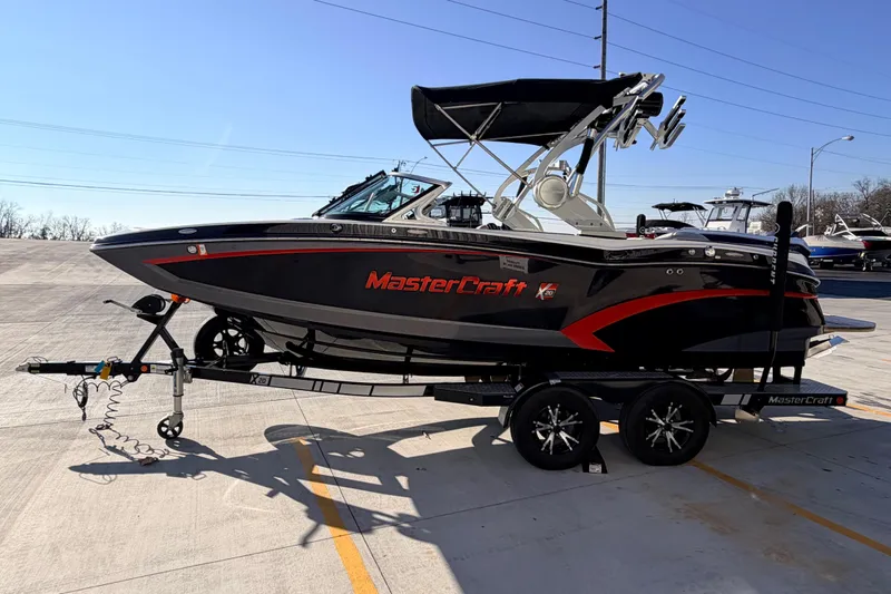 Slide: The Image of 2015 MasterCraft X20 boat on trailer, black and red design, parked outdoors. - 42