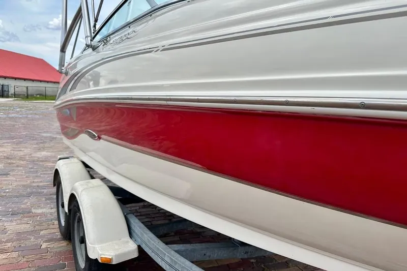Slide: The Image of 2004 Sea Ray 200 Sundeck boat on trailer, featuring red and white hull. - 10