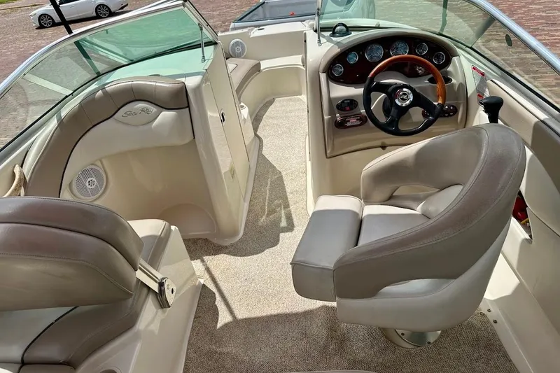 Slide: The Image of 2004 Sea Ray 200 Sundeck interior with beige seating and steering wheel. - 28
