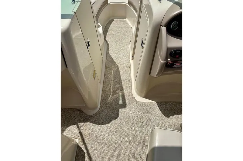 Slide: The Image of 2004 Sea Ray 200 Sundeck interior with beige carpet and storage compartments. - 29