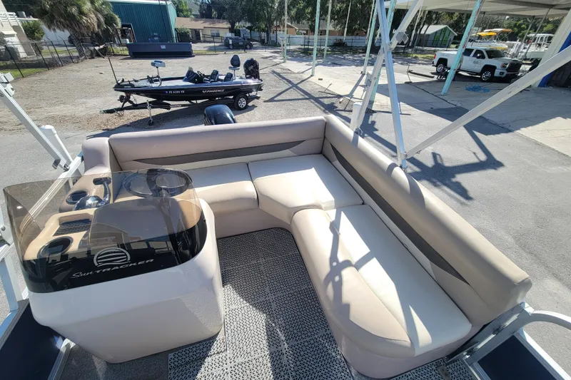 Slide: The Image of 2015 Sun Tracker Party Barge 16 DLX with beige seating and console, parked outdoors. - 9