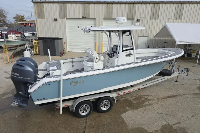 Slide: The Image of 2019 Sea Hunt Gamefish 25 boat on trailer, parked outside a warehouse. - 10