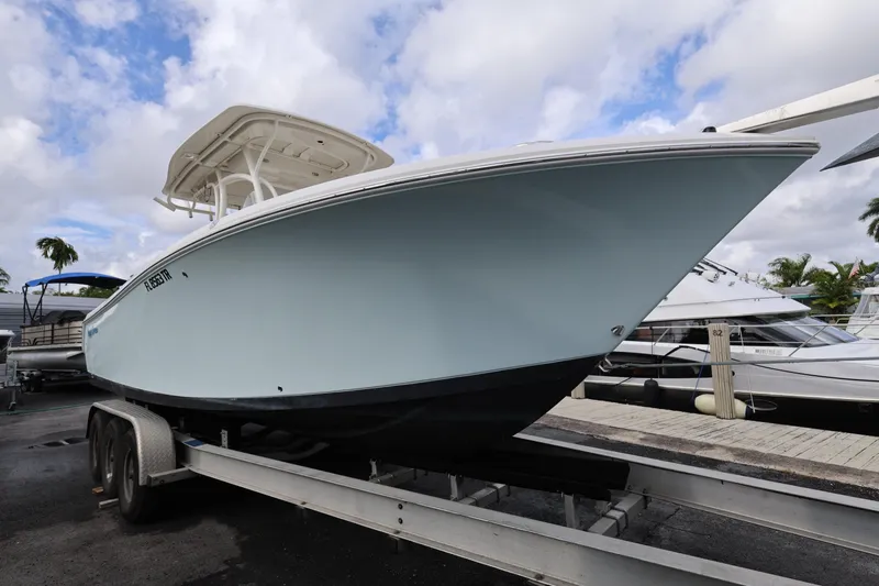 The Image of 2014 Sailfish 270 CC boat on trailer, dockside, under cloudy sky. - 0