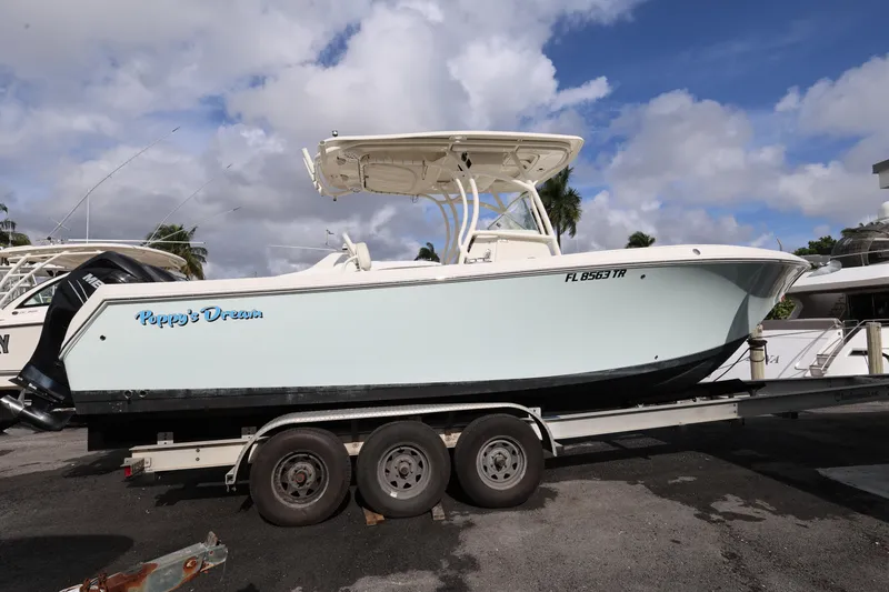 Slide: The Image of 2014 Sailfish 270 CC boat named "Poppy's Dream" on a trailer under a cloudy sky. - 2