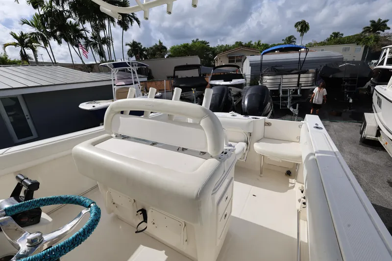 Slide: The Image of 2014 Sailfish 270 CC boat interior with white seating and steering wheel, docked outdoors. - 21