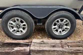 Slide: The Image of 2023 Tracker Pro Team 195 TXW Tournament Edition trailer wheels on gravel. - 15