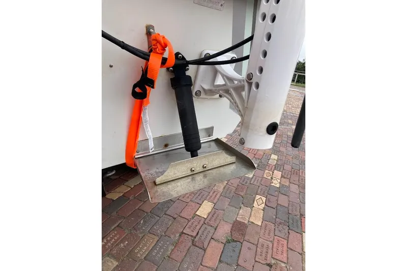 Slide: The Image of 2007 Coastal Bay 2310 boat detail with trim tab and orange strap on brick pavement. - 16