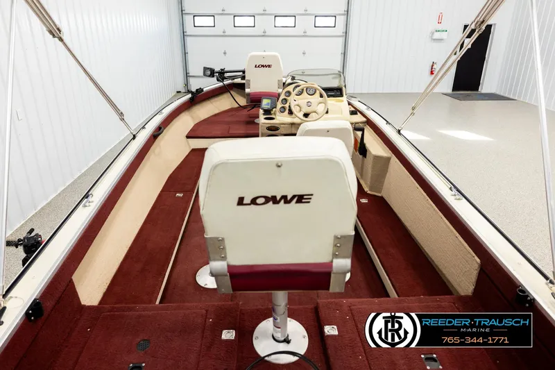 Slide: The Image of 1999 Lowe Sea Nymph V 179 SCX boat interior with red and beige seating in a garage. - 12
