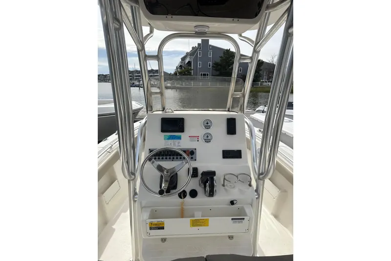Slide: The Image of 2024 Key West 239 FS boat console with steering wheel and controls, docked by waterfront. - 4