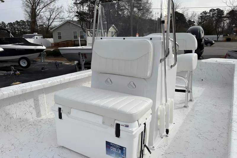 Slide: The Image of 2026 Coastal Skiff 271 boat interior with white seating and cooler, parked outdoors. - 11