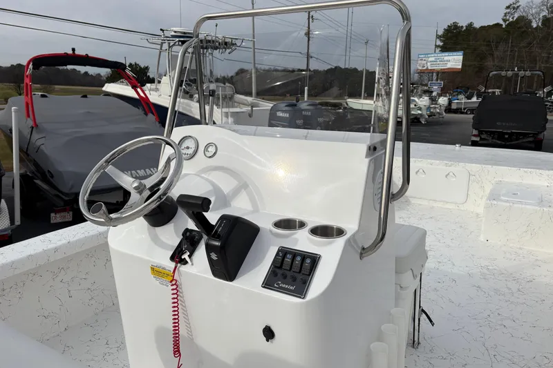 Slide: The Image of 2026 Coastal Skiff 271 boat console with steering wheel and controls, parked outdoors. - 12