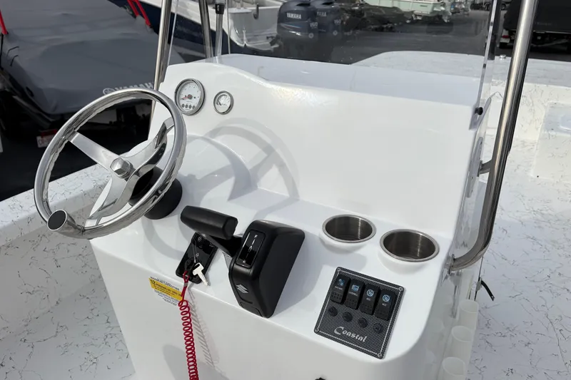 Slide: The Image of 2026 Coastal Skiff 271 boat console with steering wheel, gauges, and cup holders. - 14